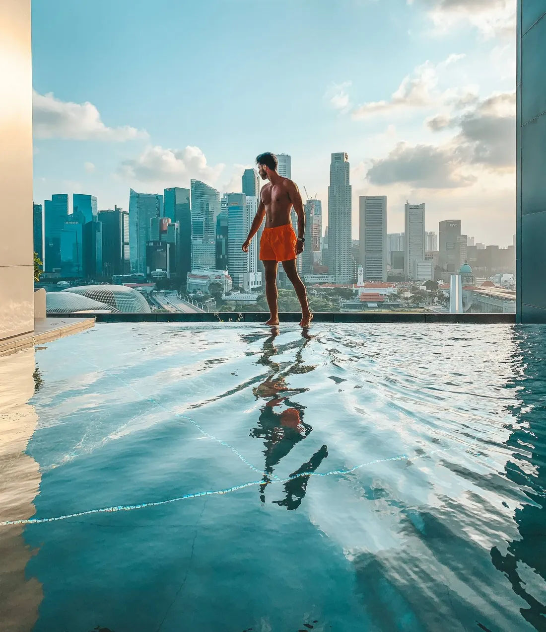 Walter at the edge of a rooftop infinity pool above the Singapore skyline